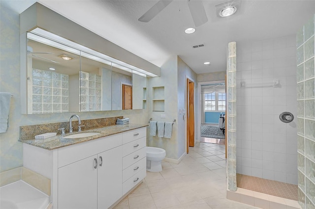 bathroom featuring ceiling fan, vanity, tiled shower, tile patterned floors, and toilet