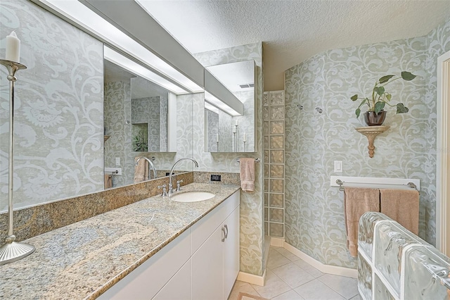 bathroom featuring tile patterned floors, a textured ceiling, a shower, and vanity