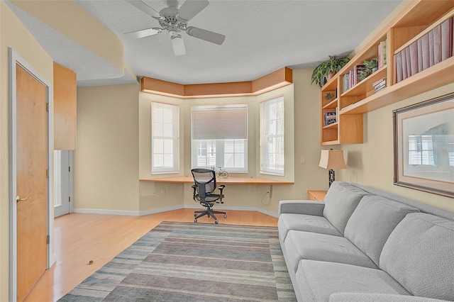 living room with ceiling fan, a textured ceiling, light wood-type flooring, and a healthy amount of sunlight