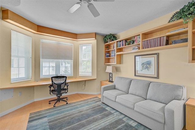 office space with built in desk, a wealth of natural light, ceiling fan, and hardwood / wood-style flooring