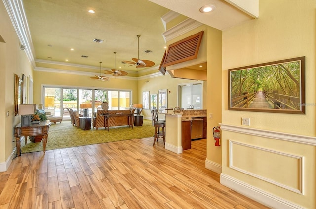 living room with crown molding, ceiling fan, and light hardwood / wood-style flooring