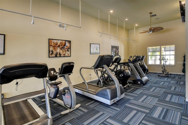 exercise room featuring a high ceiling, dark colored carpet, and ceiling fan