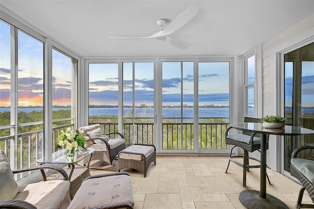 sunroom / solarium featuring a ceiling fan and a water view