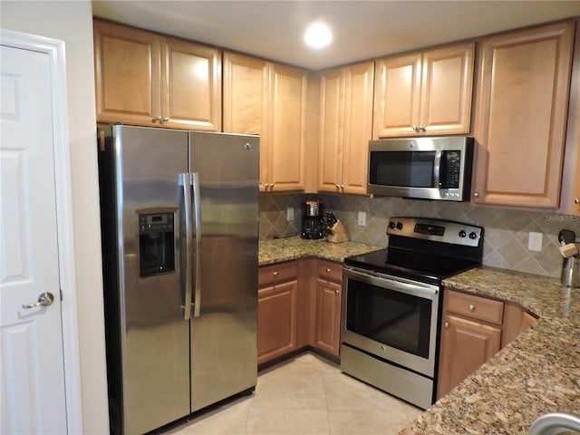 kitchen with decorative backsplash, light stone countertops, light tile patterned floors, and stainless steel appliances