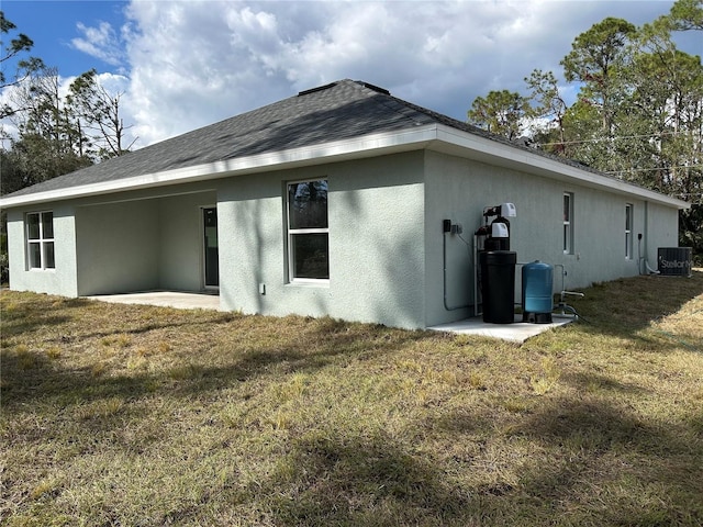 back of property with central AC unit, a patio area, and a lawn