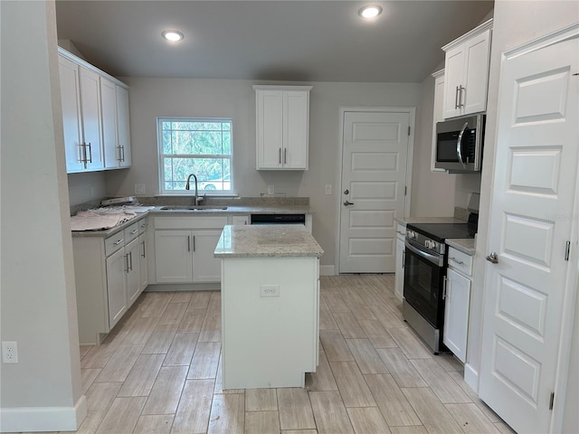 kitchen with white cabinetry, appliances with stainless steel finishes, a center island, and sink