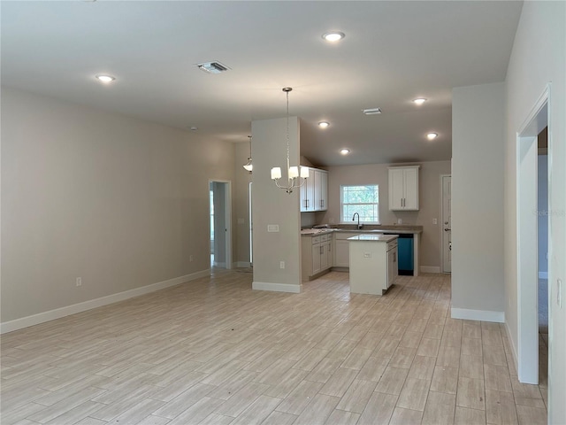 kitchen with a kitchen island, white cabinets, hanging light fixtures, a notable chandelier, and light hardwood / wood-style flooring