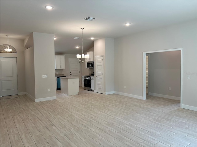 kitchen with stainless steel appliances, a center island, hanging light fixtures, and white cabinets