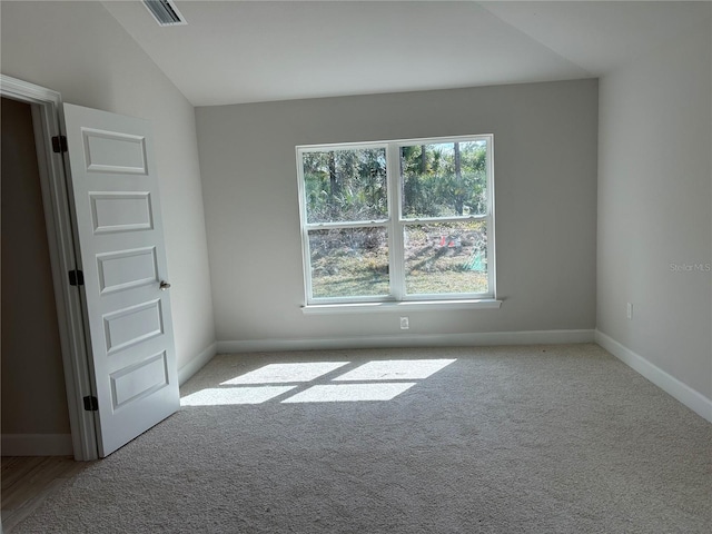 carpeted empty room with vaulted ceiling