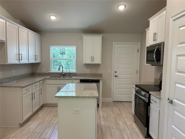5661 Gaffney Rd, North Port, FL 34286 - kitchen featuring stainless steel appliances, a center island, wood finish floors, white cabinetry, and light stone countertops