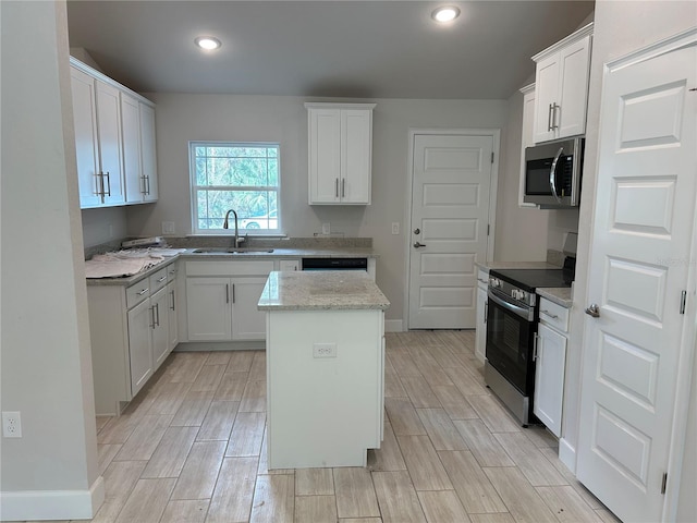 5661 Gaffney Rd, North Port, FL 34286 - kitchen featuring stainless steel appliances, wood tiled floors, white cabinetry, a center island, and recessed lighting