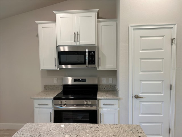 5661 Gaffney Rd, North Port, FL 34286 - kitchen featuring appliances with stainless steel finishes, white cabinetry, light stone countertops, wood finished floors, and lofted ceiling