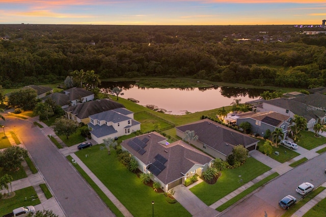 aerial view at dusk featuring a water view