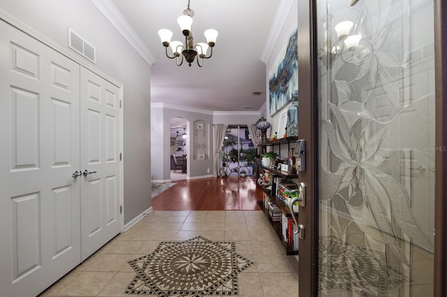 entrance foyer with light hardwood / wood-style floors, ornamental molding, and an inviting chandelier