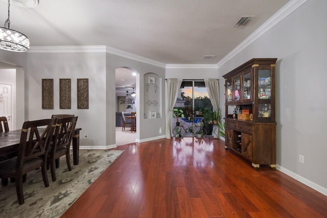 dining room with dark wood-type flooring, crown molding, and a chandelier