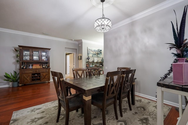 dining space featuring dark wood-type flooring, crown molding, and an inviting chandelier