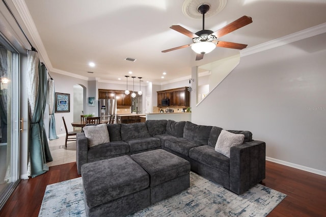 living room featuring dark wood-type flooring, crown molding, and ceiling fan