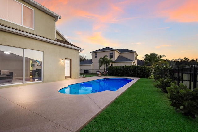 pool at dusk with a patio area and a yard