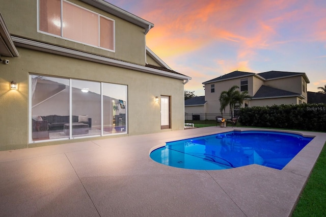 pool at dusk with a patio area