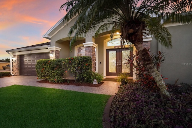 exterior entry at dusk with a lawn and a garage