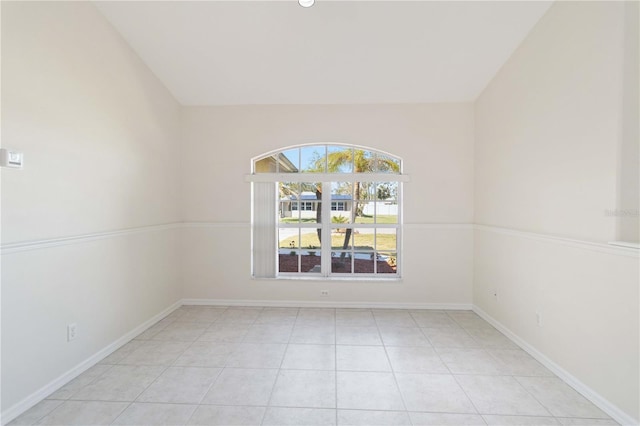 tiled spare room featuring vaulted ceiling