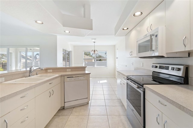 kitchen featuring white appliances, an inviting chandelier, sink, hanging light fixtures, and light tile patterned floors