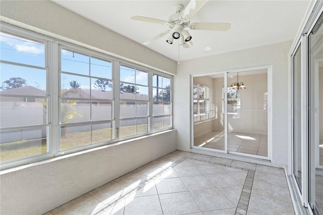 unfurnished sunroom featuring ceiling fan with notable chandelier