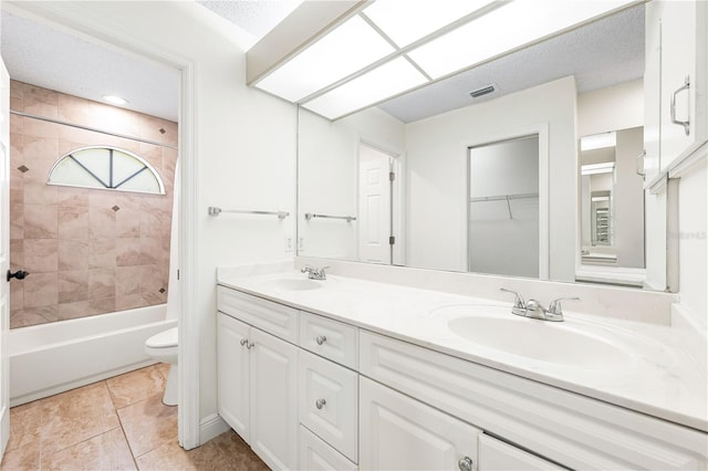 full bathroom featuring tiled shower / bath, vanity, a textured ceiling, tile patterned floors, and toilet