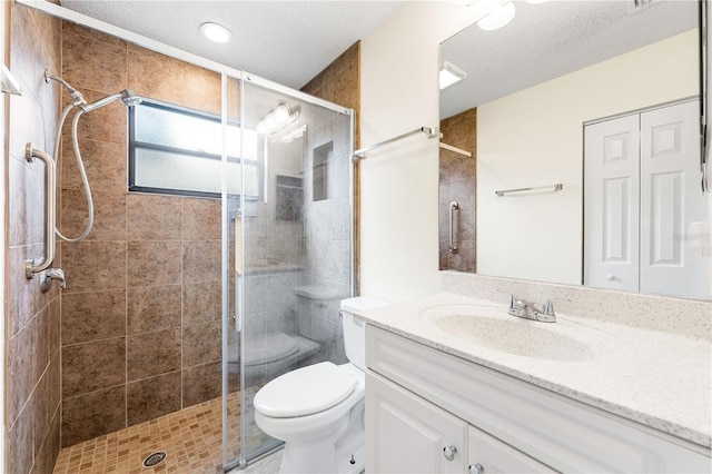 bathroom with vanity, a shower with shower door, toilet, and a textured ceiling