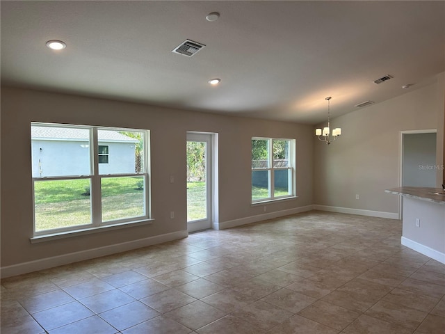 unfurnished room with vaulted ceiling, plenty of natural light, light tile patterned floors, and a notable chandelier