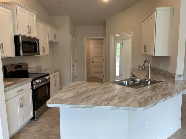 kitchen with appliances with stainless steel finishes, sink, white cabinets, light tile patterned floors, and kitchen peninsula