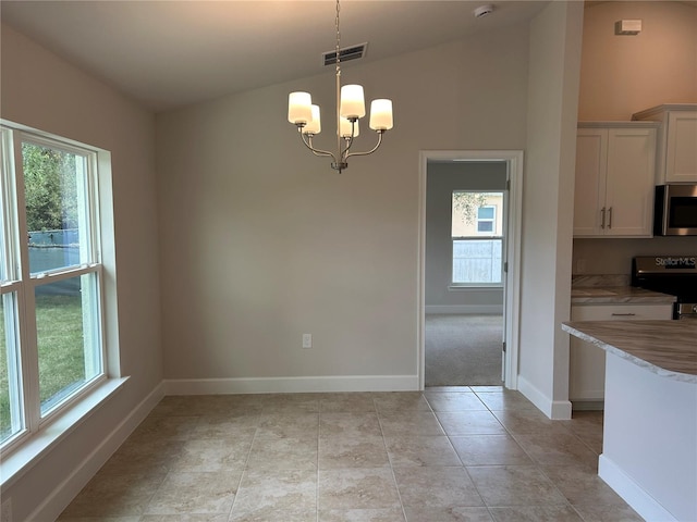 unfurnished dining area featuring light tile patterned flooring, plenty of natural light, a chandelier, and vaulted ceiling