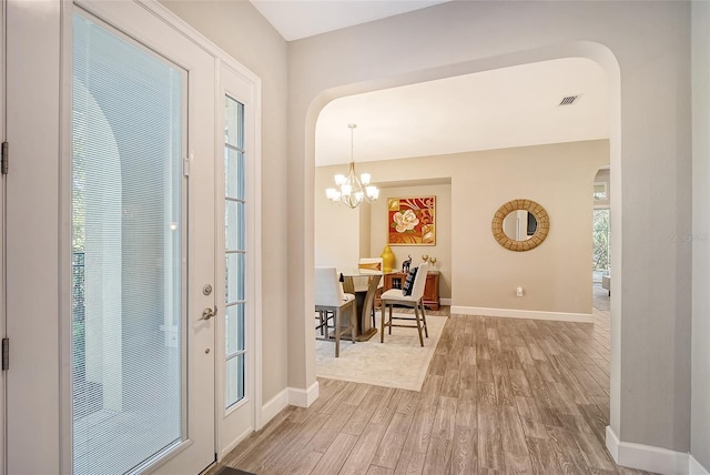 foyer with wood-type flooring and a notable chandelier