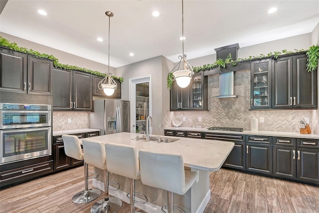 kitchen with a center island with sink, sink, light wood-type flooring, and appliances with stainless steel finishes