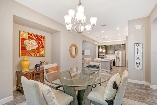 dining room with light hardwood / wood-style floors, a chandelier, and sink