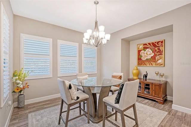 dining room with light wood-type flooring and an inviting chandelier