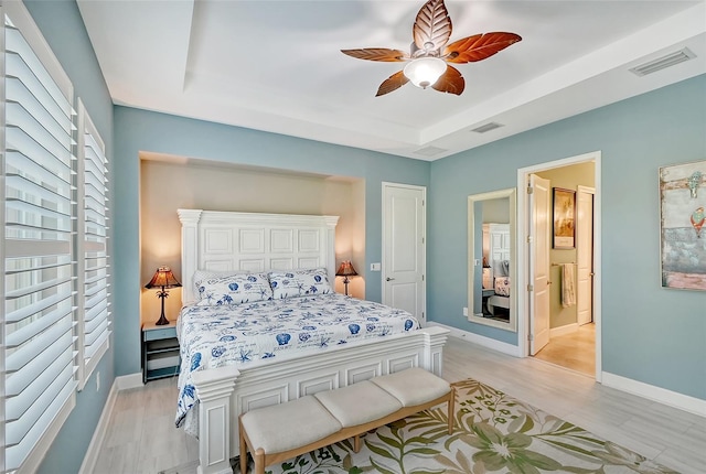 bedroom with ceiling fan, ensuite bath, and light wood-type flooring