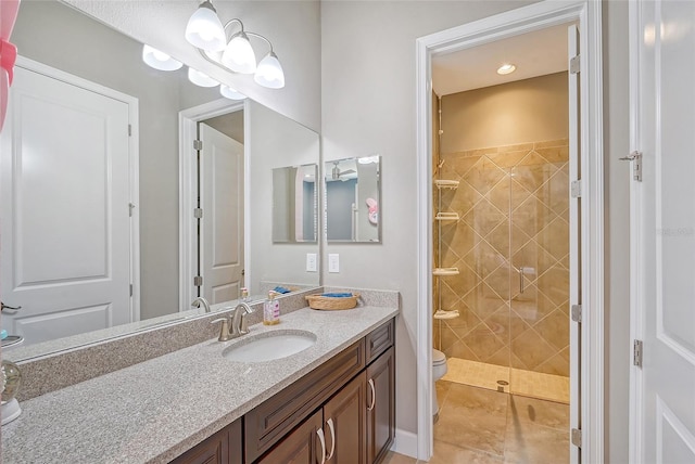 bathroom with toilet, vanity, tile patterned floors, and a tile shower