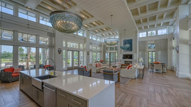 kitchen with a high ceiling, plenty of natural light, sink, and a kitchen island with sink