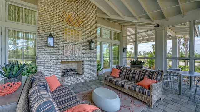 sunroom / solarium featuring lofted ceiling with beams and an outdoor brick fireplace