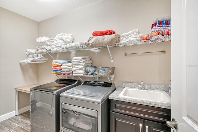 washroom with cabinets, light hardwood / wood-style floors, sink, and washing machine and clothes dryer