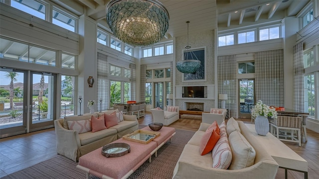 sunroom / solarium featuring an inviting chandelier, beam ceiling, and a large fireplace