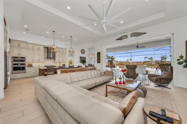 living room with ceiling fan, crown molding, and a tray ceiling