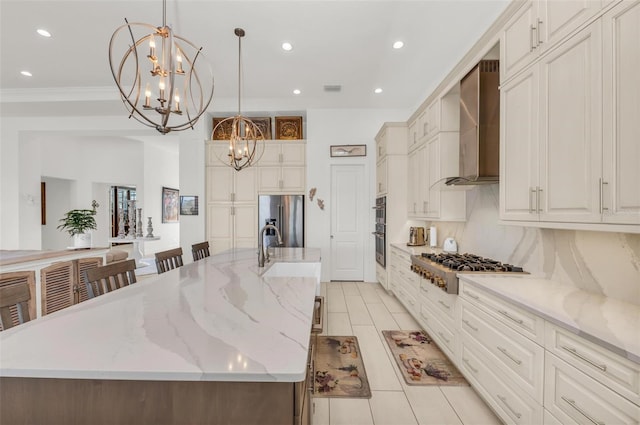 kitchen with decorative light fixtures, appliances with stainless steel finishes, wall chimney range hood, and a large island