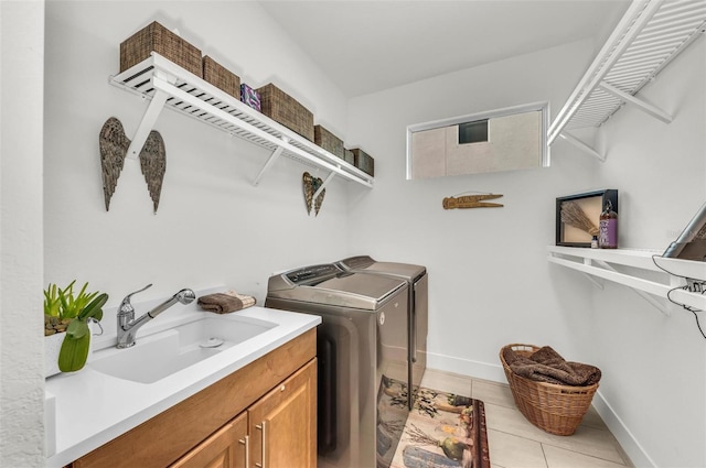 laundry area featuring cabinets, light tile patterned floors, washer and clothes dryer, and sink