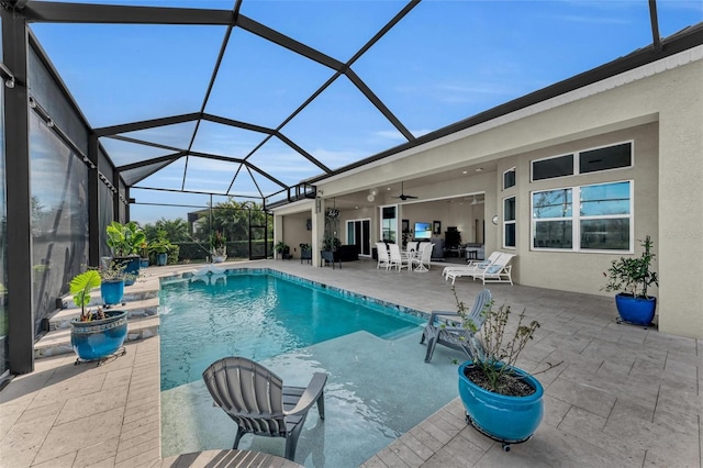 view of pool with glass enclosure, ceiling fan, and a patio