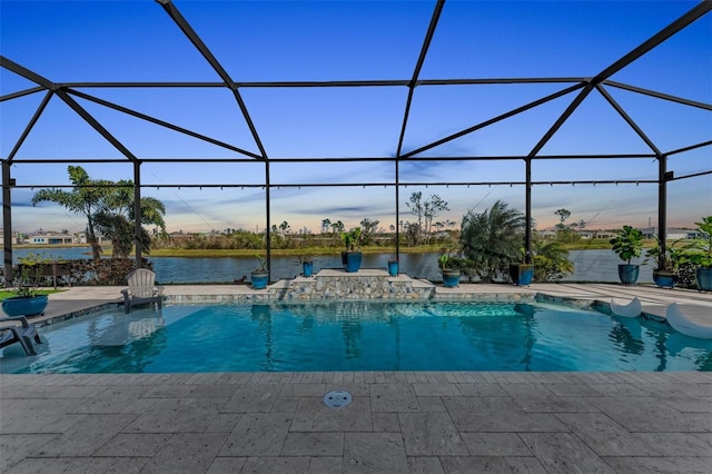 pool at dusk with a lanai, a patio area, and a water view