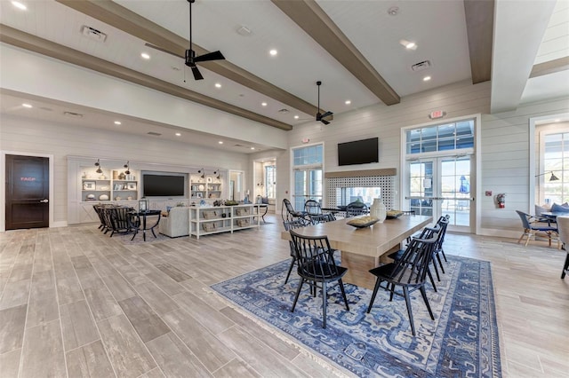 dining room featuring ceiling fan, wood walls, beam ceiling, and french doors