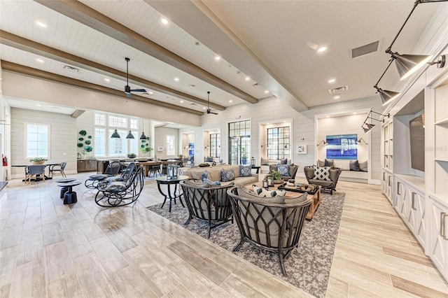 living room featuring ceiling fan, beamed ceiling, and wooden walls