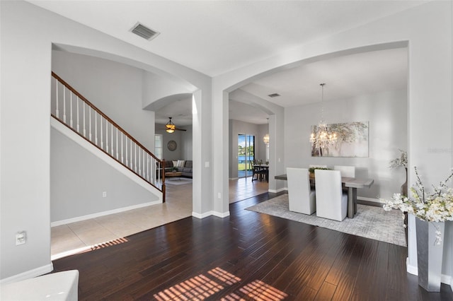 entryway with ceiling fan with notable chandelier and wood-type flooring